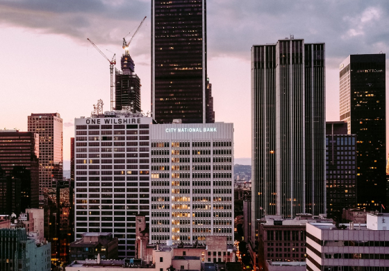 A group of high end buildings with sun rising from behind