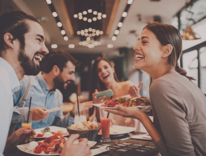 A group of friends laughing and enjoying a meal in a restaurant.